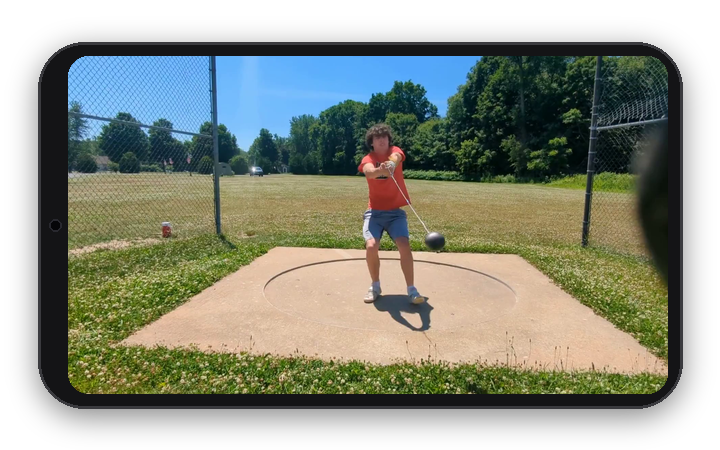 Phone in landscape orientation showing a video frame of a hammer thrower at practice, mid-turn